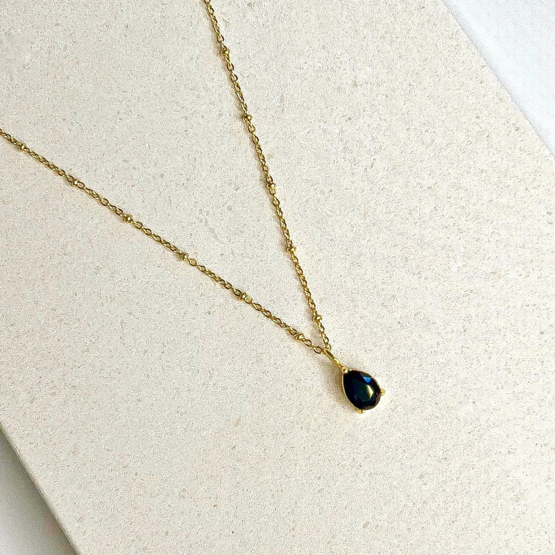Dark blue/black pendant on gold plated chain.